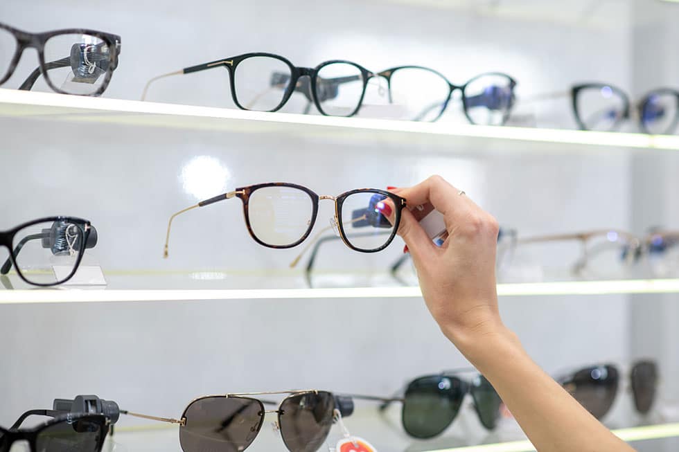 Woman picking up eyeglasses from a shelf